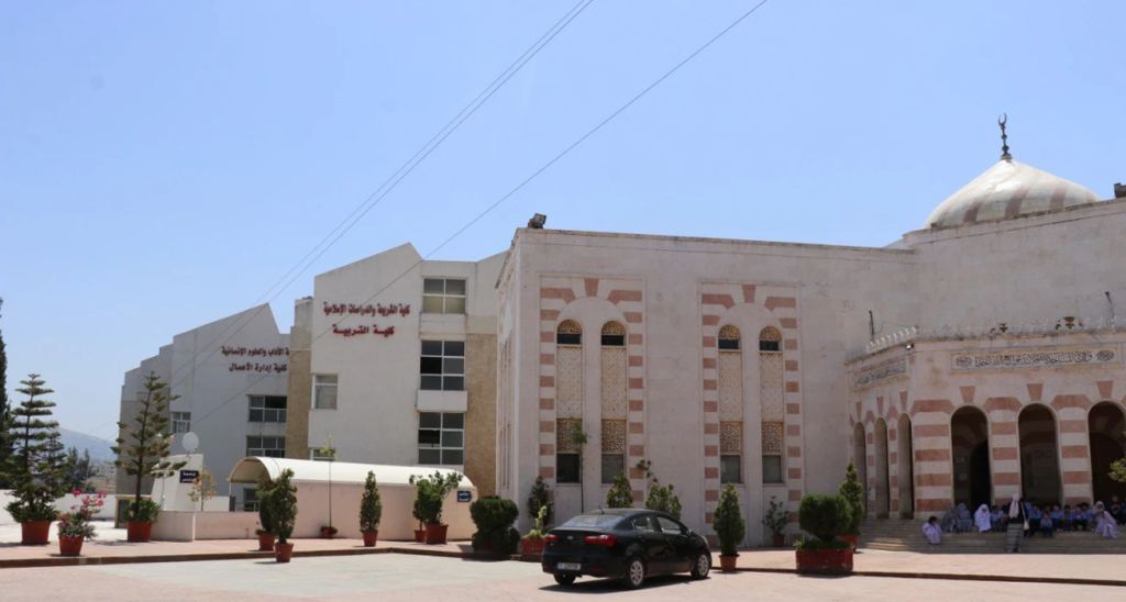 كلية الشريعة والدراسات الإسلامية، وقبة مسجدها من الحجر المخطط بالوردي والأبيض، وطلاب على الدرج